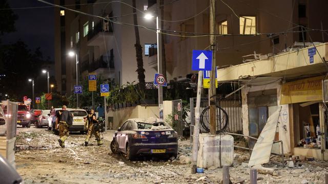 Members of the Israeli security forces walk along a debris-strewn street in Tel Aviv, after it was hit by a rocket fired by Palestinian militants from the Gaza Strip on October 7, 2023. 